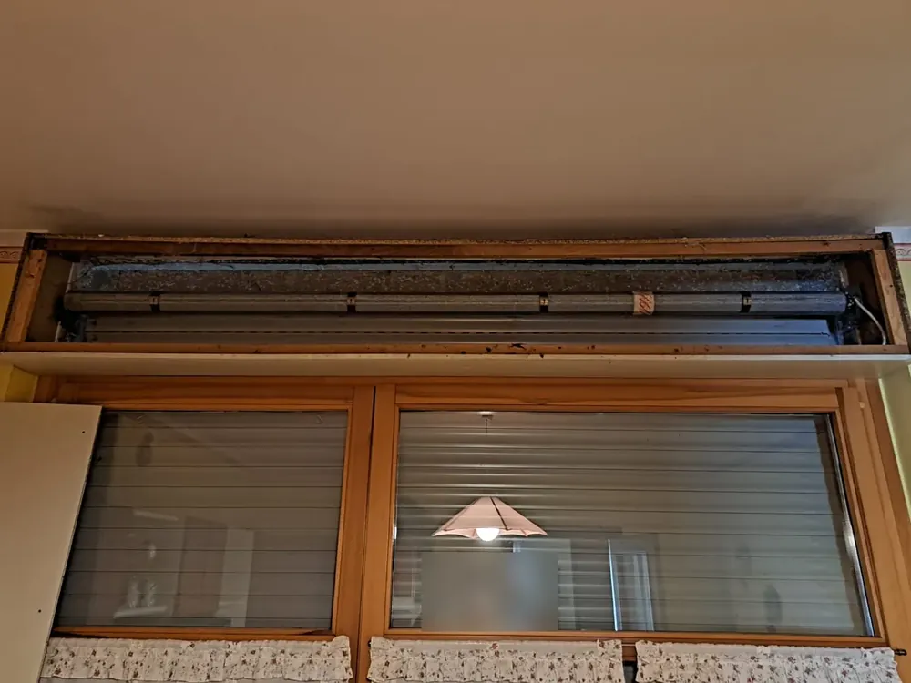 Riparazione tapparelle a Rovigo: cassonetto aperto sopra una porta finestra con rullo e motore