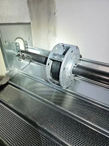 Riparazione serrande ad Adria: albero con molla di bilanciamento di una serranda microforata